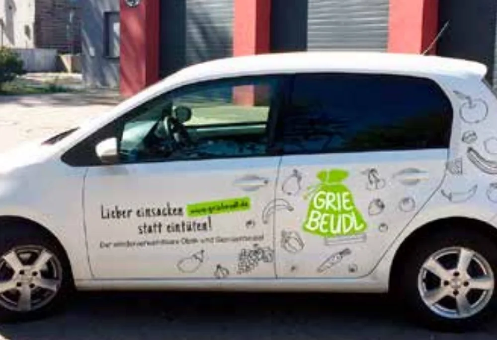 Weißes Auto mit Griebeudl-Beschriftung und Gemüse-Illustrationen